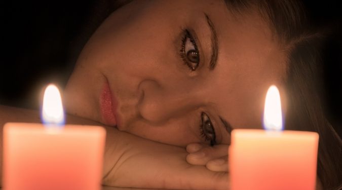 Depressed woman by lit candles