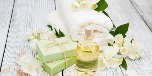 white flowers with bottle of essential oil and bar soap