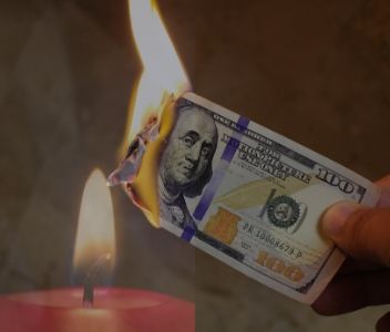 Red burning candle catching money on fire