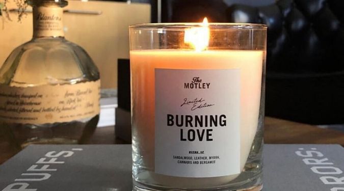 The Motley Burning Love white soy candle burning on desk