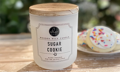 DW Home Sugar Cookie candle with wooden lid beside decorated sugar cookies