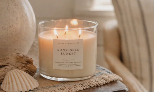 Copper Candle Co. Sunkissed Sunset soy candle in a clear glass vessel with coastal-inspired decor