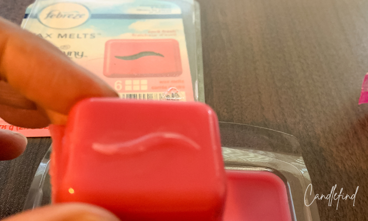 Single cube of Febreze April Fresh wax melt held above opened wax melt package